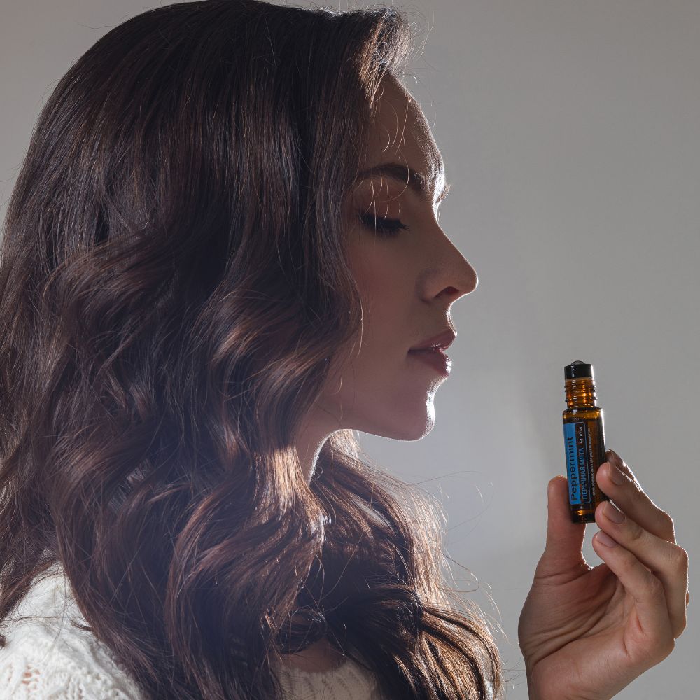 Woman holding peppermint essential oil roller bottle in sunlight