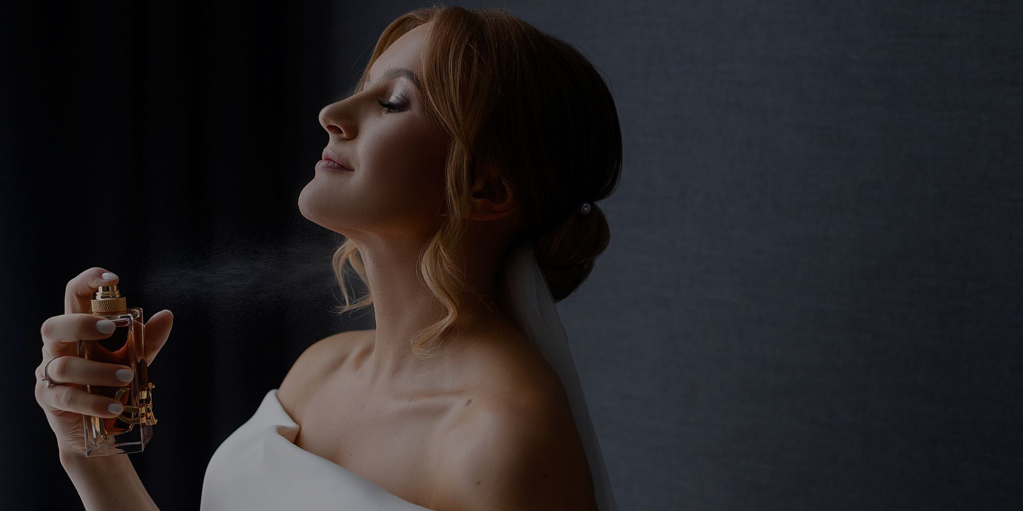 Elegant woman with eyes closed spraying perfume on her neck